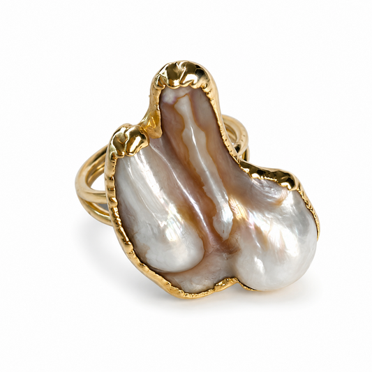 A gold ring featuring a large, organic-shaped baroque pearl inlay with natural brown and white marbling, set against a clean white background.