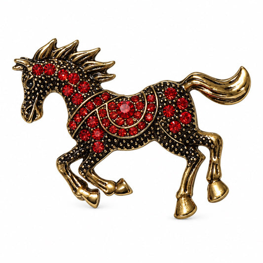 A gold-toned horse-shaped brooch or pin embellished with red rhinestones on a plain white background.